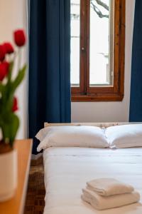 a white bed with a window and a vase with red roses at Eventi e Relax vicino all'Artemio Franchi e al Centro Storico in Florence