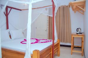 a bedroom with a canopy bed with pink flowers on it at Suda Beach Lodge in Kumba Urembo