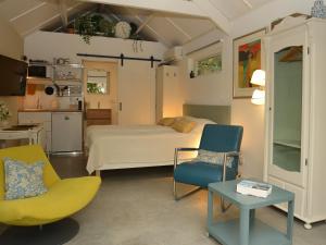 ein Schlafzimmer mit einem Bett und zwei Stühlen und einem Tisch in der Unterkunft De Weie in Burgh Haamstede