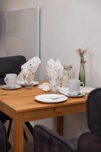 a wooden table with two cups and plates on it at Hinterhaus in Herdwangen +1 photo