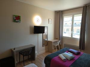 a bedroom with a bed and a tv and a window at Hôtel De La Gare Périgueux in Périgueux