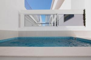 a swimming pool with a window in a house at The Olive Tree Apartment in Tavira