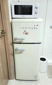 einen weißen Kühlschrank mit einer Mikrowelle darüber in der Unterkunft Green Bring in Daegu