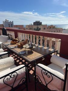 a table on a balcony with a view of the ocean at Town Gate in Tamraght Ouzdar