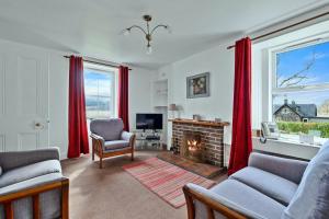 Finest Retreats - Lochead Cottage في Achahoish: غرفة معيشة مع موقد وستائر حمراء