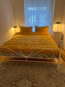 a bedroom with a large bed with yellow sheets and a window at Capital Apartmani Zagreb 2 in Zagreb