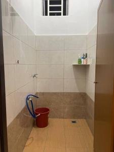 a bucket in the corner of a shower in a bathroom at Nona Homestay in Parit Buntar