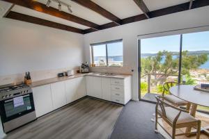 a kitchen with white cabinets and a table and a window at Little Innes in Albany