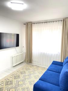 ein Wohnzimmer mit einem blauen Sofa und einem Fernseher in der Unterkunft The Bishkek Nest in Bischkek
