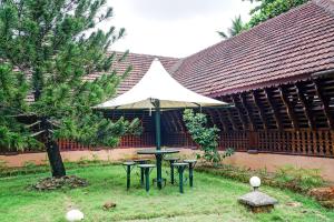 a picnic table with an umbrella in a yard at Palette - Pagoda Resorts in Cochin