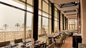 a dining room with tables and chairs and large windows at Phoenicia Residence in Beirut