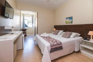 a hotel room with a bed and a kitchen at Hotel Fabris in Nova Friburgo