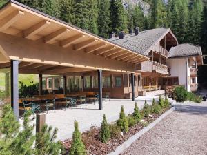 a large wooden house with a patio and tables and chairs at Hotel Villetta Maria Cottage in Canazei