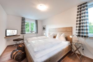 a bedroom with a large white bed with a wooden headboard at Bayern Resort Apartments in Grainau +65 photos