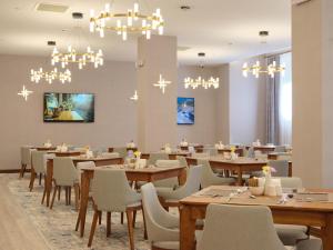 a dining room with tables and chairs and chandeliers at The Central Point Hotel Baku in Baku