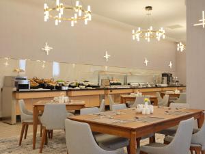 a dining room with tables and chairs and a kitchen at The Central Point Hotel Baku in Baku