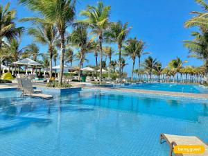 a large swimming pool with palm trees in a resort at Mandara Lanai Resort - Porto das Dunas in Aquiraz