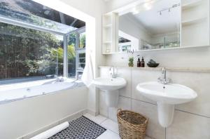 un bagno con due lavandini, una vasca e una finestra di Miracle Villa a Kenton-on-Sea