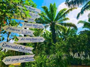 ein Straßenschild mit vielen Schildern vor einer Palme in der Unterkunft Golden Palm Resort in Krabi