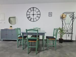 a table and chairs with a clock on a wall at Gîte du Hibou in Mont-Saint-Martin