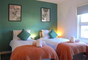 zwei Betten in einem Zimmer mit grünen Wänden in der Unterkunft Hope Cottage In Slough With Parking in Slough