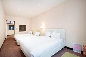 two large white beds in a hotel room at OH Homes - Samsen 12 in Bangkok
