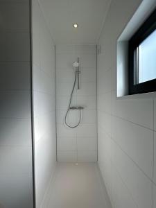 a shower in a white bathroom with a window at Wellnesslodge Kievit in Dalerveen +29 photos