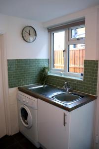 eine Küche mit einem Waschbecken, einem Fenster und einer Waschmaschine in der Unterkunft Hope Cottage In Slough With Parking in Slough + 16 Fotos