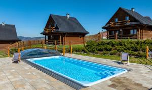 a swimming pool in front of a house at Domki Zagroda Domek z bala z basenem & sauna & balia z hydromasażem in Słopnice
