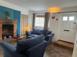 un soggiorno con mobili blu e camino di Cosy Little Cottage a Woodbridge