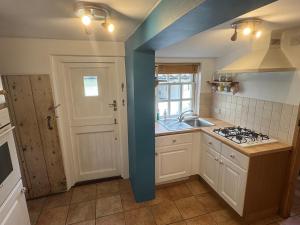 una cucina con parete blu e piano cottura forno superiore di Cosy Little Cottage a Woodbridge