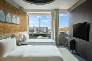 Una habitación de hotel con dos camas y un televisor de pantalla plana. en The Westin Doha Hotel & Spa, en Doha
