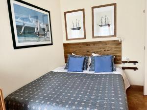 a bedroom with a bed with blue pillows and pictures at Primera Linea de Playa con vistas al Mar in Águilas