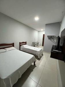 a hotel room with two beds and a television at Apartamento 103 - Suíte com ar condicionado in Patos de Minas