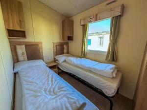 two beds in a small room with a window at Lovely 6 Berth Caravan Nearby Hunstanton Beach In Norfolk Ref 23071T in Hunstanton