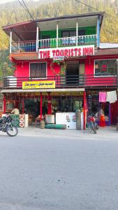 a red building with a sign that reads the tourists inn at The Tourists Inn in Chak