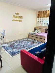 a room with two beds and a red couch at Single private room with shared washroom and kitchen in Sharjah