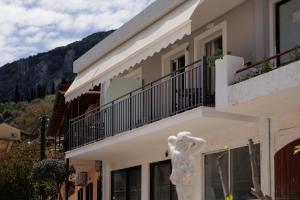 - un bâtiment blanc avec un balcon et des montagnes en arrière-plan dans l'établissement Plaka Studios 2, à Benitses