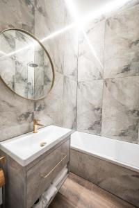 une salle de bain avec un lavabo, une baignoire et un miroir dans l'établissement Stylish property, Self check in 24h, Netflix, parking, à Vilnius