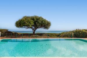 a swimming pool with a tree in the background at Townhouse Crystal Bay by Algarve Vacation in Benagil