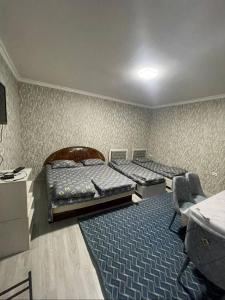 Una habitación con dos camas y una silla dentro. en Nur Xostel, en Samarkand
