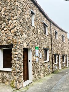 - un vieux bâtiment en pierre avec une porte et des fenêtres dans l'établissement Los Nidos de Nines, à Cabezabellosa