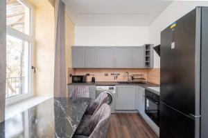 une cuisine avec des armoires blanches et un réfrigérateur noir dans l'établissement Stylish property, Self check in 24h, Netflix, parking, à Vilnius 17 autres photos