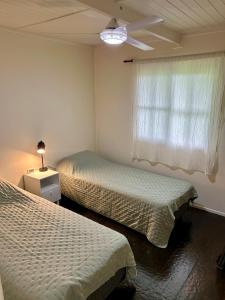a bedroom with two beds and a window with a ceiling fan at Las Luciérnagas del Delta 1 in Tigre