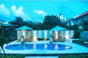 a swimming pool at night with umbrellas at Nada Garden villa in Jinengdalem