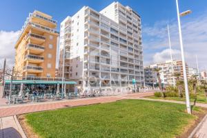 a tall building with tables and chairs in a park at Apartamento Vista Al Mar in Puerto de Gandía