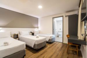 a hotel room with two beds and a bathroom at Uniclass Hotel Lapa in São Paulo