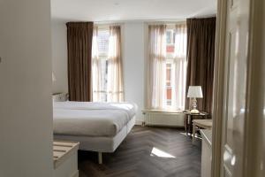 a hotel room with a bed and two windows at Hotel Schimmelpenninck Huys in Groningen