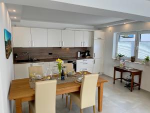 a kitchen with a wooden table and white cabinets at Ferienwohnung RebenFREUND in Bad Neuenahr-Ahrweiler