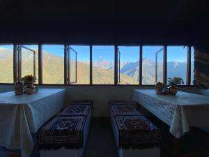 two tables in a room with a view of mountains at Hill Garden Homestay in Uttarey